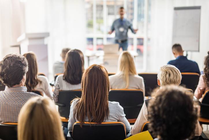 Back view of large group of business people having a training class in a board room.